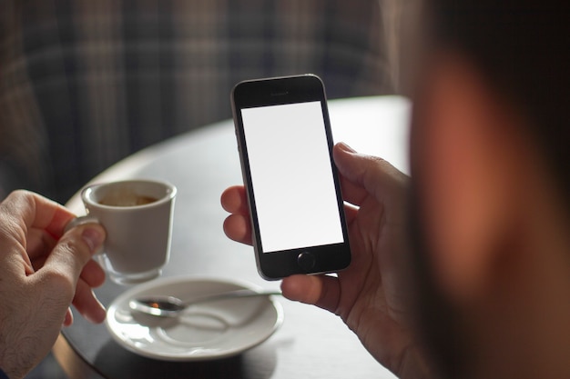 Businessman with a cup of coffee and a phone with copyspace in his hand