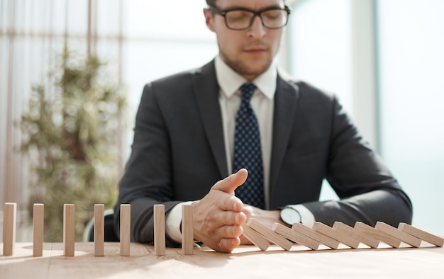 Businessman with dominoes in the office concept business risk