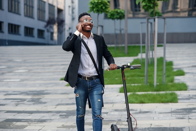 Businessman with electric scooter near a business building