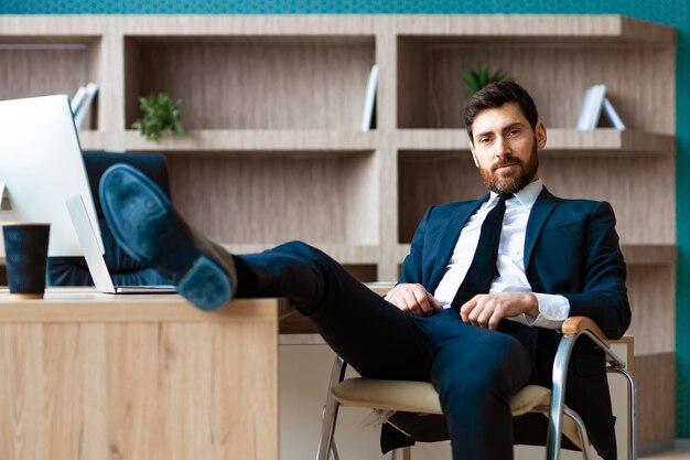 Businessman with elegant suit sitting at computer desk in the office - Adult man relax at work, concepts about business and technology