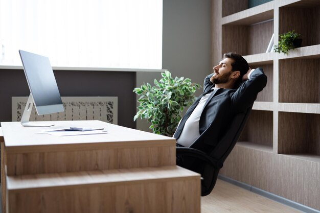 Бизнесмен в элегантном костюме сидит за компьютерным столом в офисе
