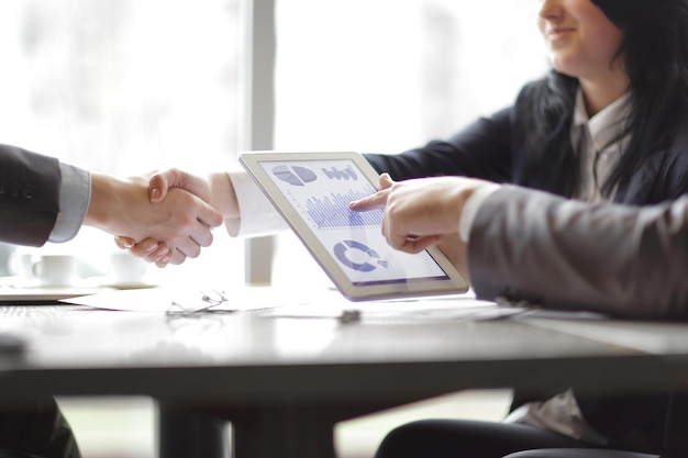 Foto uomo d'affari con un programma finanziario sullo sfondo di una stretta di mano di partner commerciali