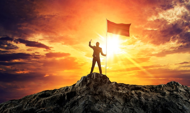 Businessman with flag on mountain top