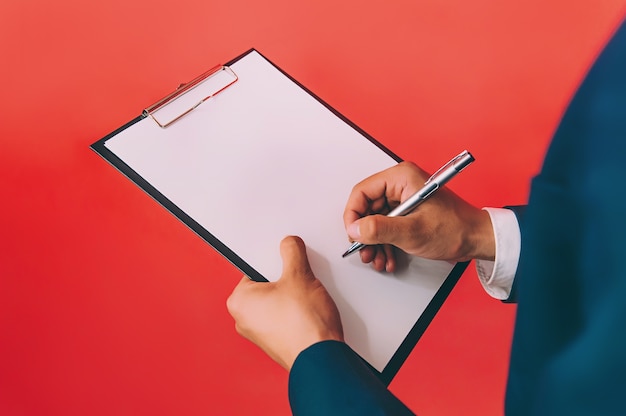 Businessman with a folder for documents in hands, on a red space.