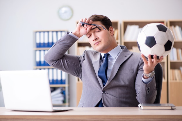 Бизнесмен с футбольным мячом в офисе