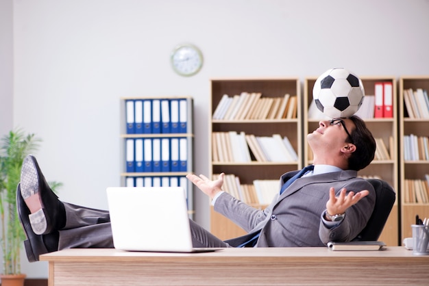 Бизнесмен с футбольным мячом в офисе