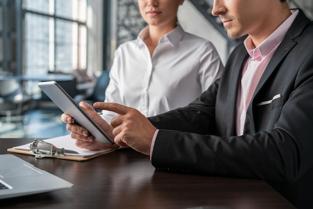 オフィスの服で女性のパートナーと手に灰色のデジタルタブレットを持つビジネスマンオフィスルームのデバイスで男性の手のクローズアップオフィスデバイスのオフィスルームのコンセプトで2人のビジネスマン