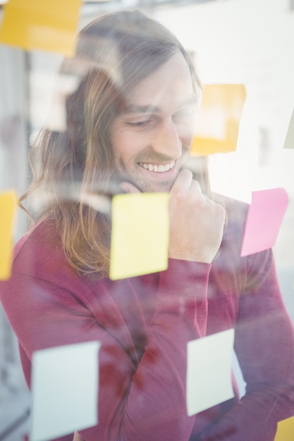 Businessman with hand on chin looking at sticky notes