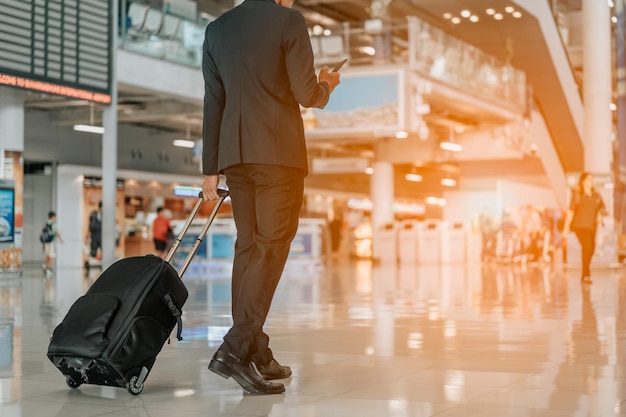 공항 터미널에서 여행 가방을 들고 사업가입니다. 공항에서 여객 출발 터미널을 걷는 동안 가방을 들고 사업가입니다. 사업가 여행자 여행 비즈니스 여행.