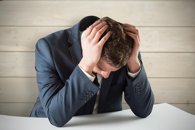 businessman with head in hands against bleached wooden planks background