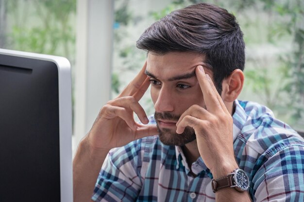 Foto uomo d'affari con la testa tra le mani che usa il computer in ufficio
