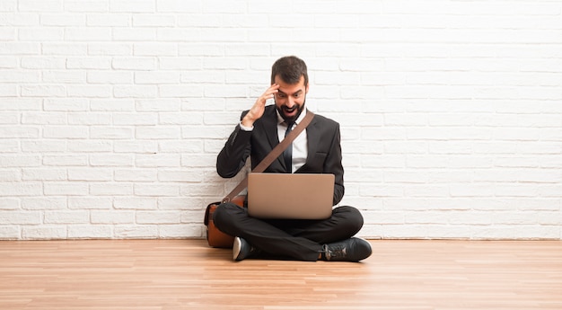 Businessman with his laptop sitting on the floor has just realized something and has intending the solution