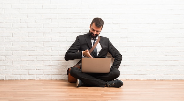 Businessman with his laptop sitting on the floor shaking hands for closing a good deal