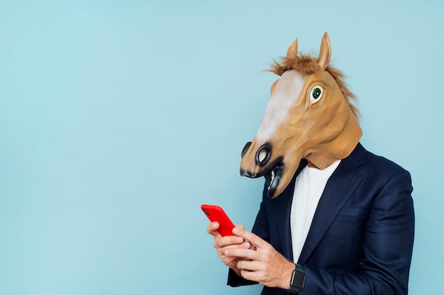 Businessman with horse mask using smartphone