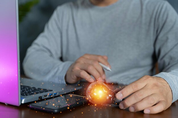 Photo businessman with illuminated light bulb working on laptop at office cropped concept for idea innovation and inspiration in business business opportunities copy space