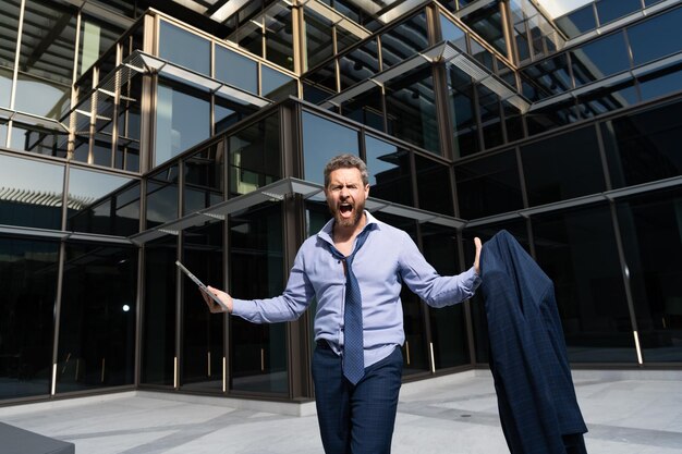 Businessman with jacket and computer shouting suffering from emotional pain emotions