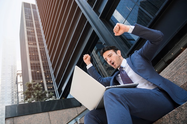 Foto uomo d'affari con laptop che celebra il successo