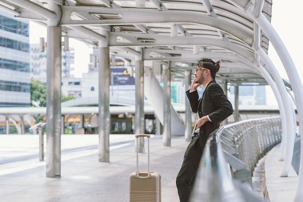 写真 都市の歩道橋で電話で話している荷物を持ったビジネスマン