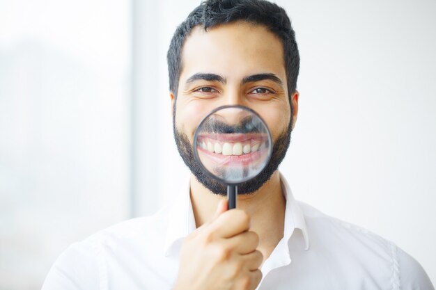 Uomo d'affari con lente d'ingrandimento che ingrandisce il suo sorriso