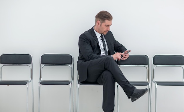 Businessman with mobile sitting in the office hallway