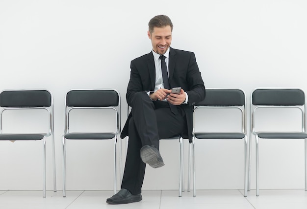 Businessman with mobile sitting in the office hallwayphoto with copy space