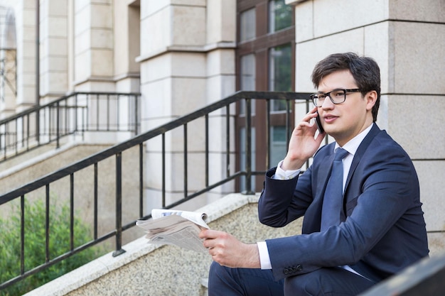 Businessman with newspaper on phone