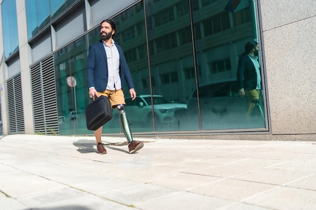 Businessman with prosthetic leg carrying laptop bag walking outdoors