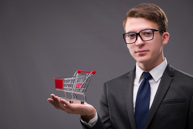 Businessman with shopping cart on gray background