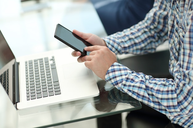 Businessman with a smartphone sitting at his Desk