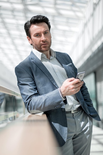 Businessman with smartphone standing in the airport building business trip