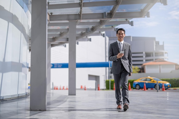 Foto uomo d'affari con lo smartphone che cammina contro la strada sfocata sullo sfondo dell'edificio, fashion business.