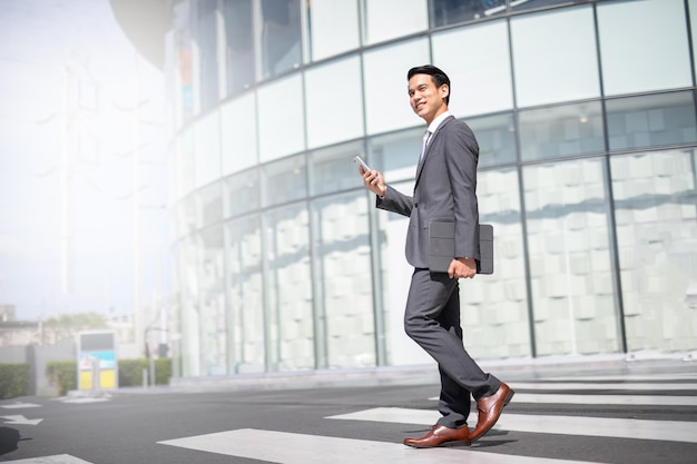 Photo businessman with smartphone walking against street blurred building background, fashion business .