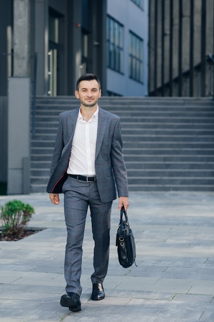 Businessman with suitcase. Full length of confident young businessmen in carrying a suitcase.