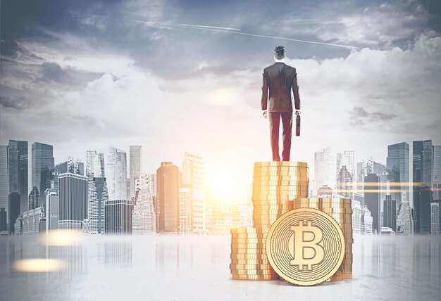 Businessman with a suitcase standing on a stack of large bitcoins looking at a cityscape. concept of blockchain. mock up toned image double exposure