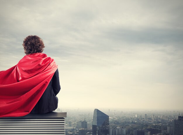 Businessman with a superhero cape view from above the city