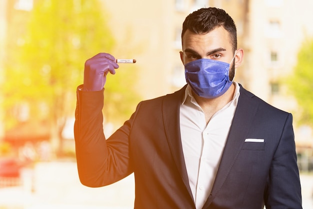 Foto uomo d'affari con maschera chirurgica e guanti che tiene una provetta per analisi del sangue che è firmata come negativa covid-19