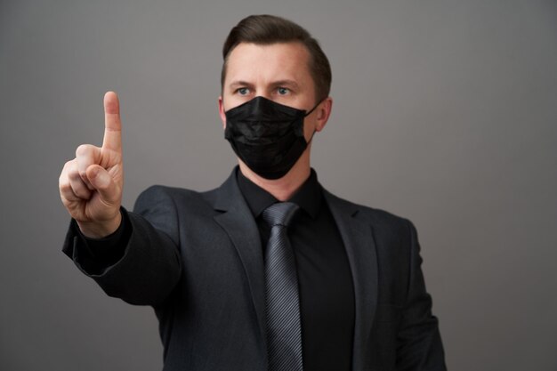 指で指している外科医療マスクを持ったビジネスマン
