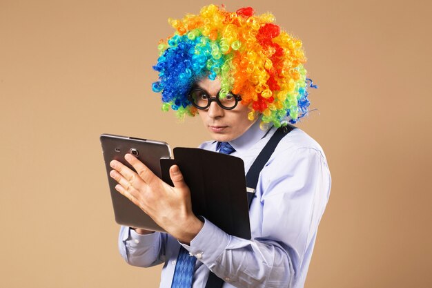 Businessman with tablet computer. Close-up Portrait of business man in clown wig using a tablet to access the internet. Business concept. Multitasking