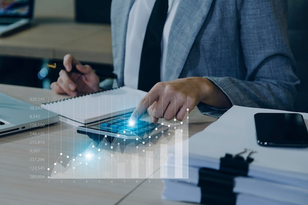 Businessman with a tablet in his hand and touching on the\
screen that shows a business graph the concept of starting a new\
business that goes better