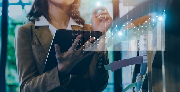 Businessman with a tablet in his hand and touching on the\
screen that shows a business graph the concept of starting a new\
business that goes better