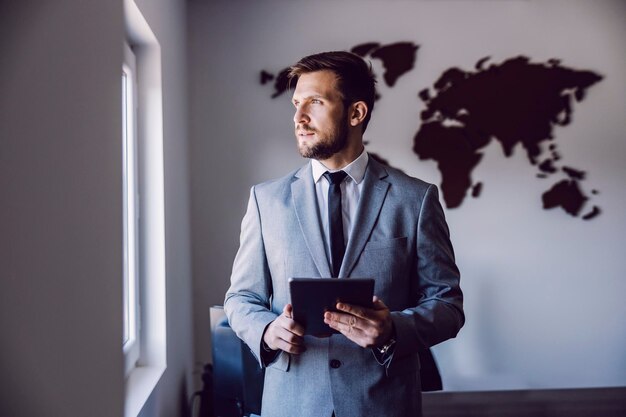 A businessman with tablet poses at the office