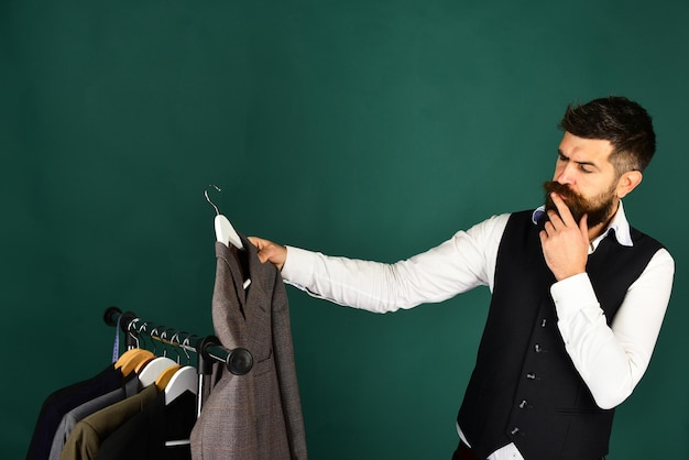 Photo businessman with thoughtful face near jackets on green background