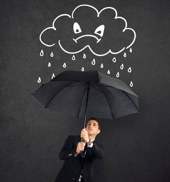 Бизнесмен с зонтиком и сердитым облаком с дождем Концепция кризиса и финансовых проблем