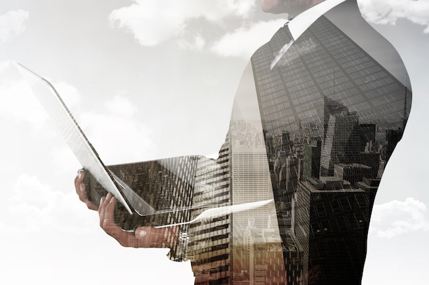 Businessman with watch using tablet pc against low angle view of skyscrapers