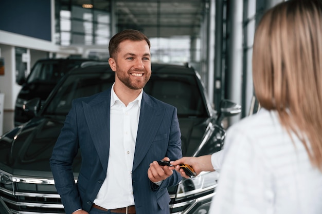 Photo businessman and woman are in a car dealership