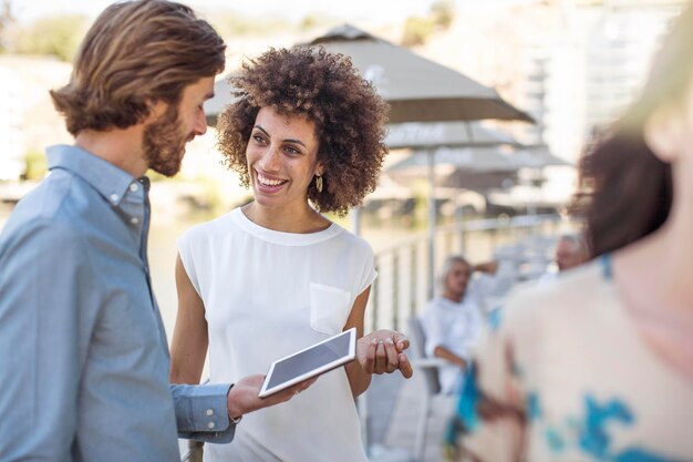 Businessman and woman having a meeting outdoors, using digital tablet