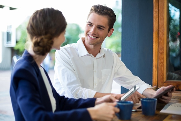 Businessman and woman interacting while having coffee at counter