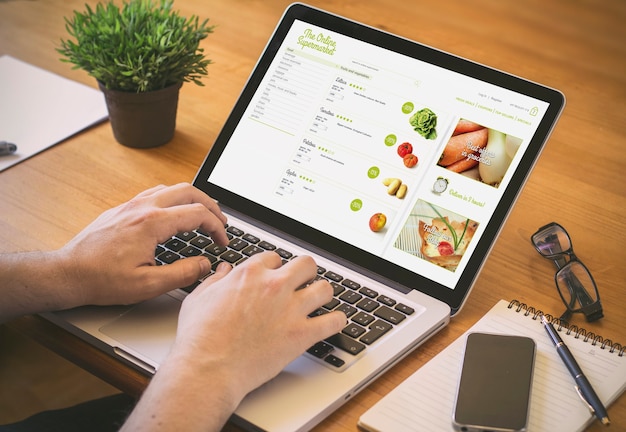 Businessman at work. Close-up top view of man shooping online on laptop while sitting at the wooden desk. Clean screen.