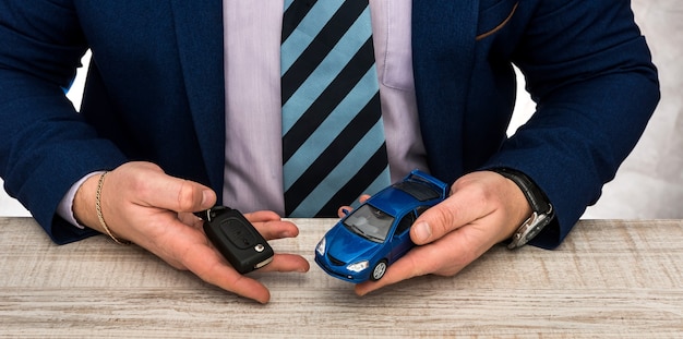 Businessman work at office - toy car and keys - sale or rent auto concept