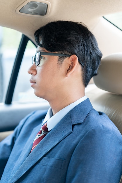 Businessman working in the backseat of a car 